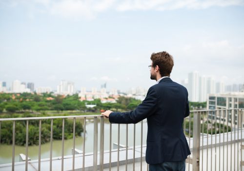 Businessman standing on balcony at looking at the city